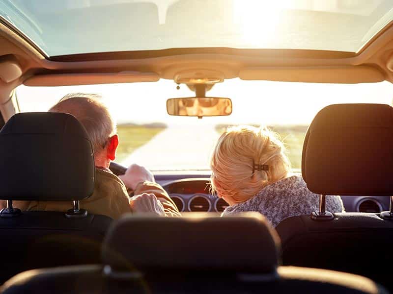 Two older adults driving through the countryside