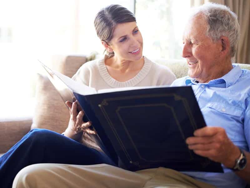 Photo: A woman and an older man look at a photo album