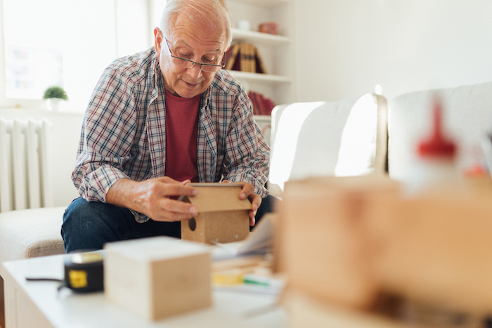 Senior man and grandfather embracing aging and enjoying his golden years while exploring his hobby of wood working and making bird houses while living at Jackson Creek senior living community